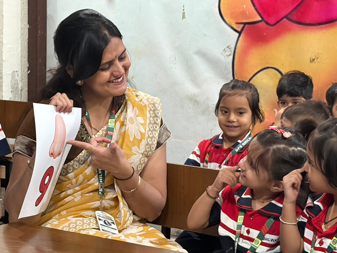 Teacher showing a number 9 activity card to Junior Wing students